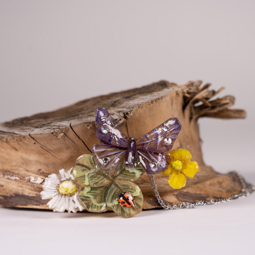 Gioiello artigianale in resina con fiori, farfalla e vero quadrifoglio